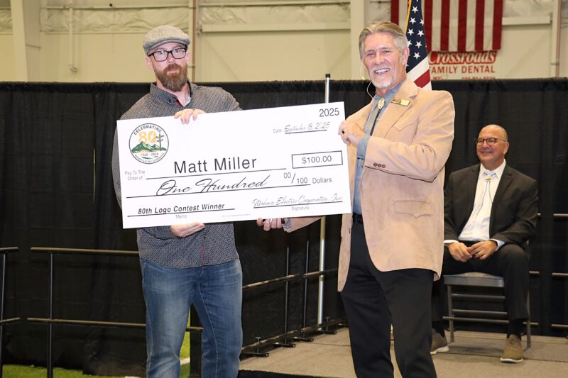 CEO Tyler Carlson congratulates Matt Miller with a $100 prize for his winning entry in MEC’s 80th Logo Contest.