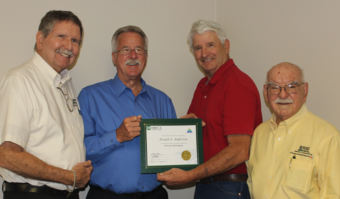 Board Director Michael Bartelt (left) joins Carlos Tejeda (right) as John Nelssen presents the Gold Director Certificate to fellow Director Joe Anderson (second from left)